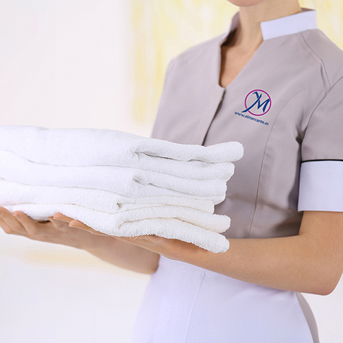 Chambermaid holding pile of clean towels in the room, closeup